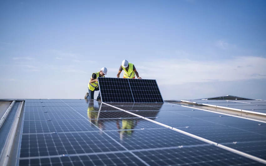 A solar panel is maintained on the roof by two workers